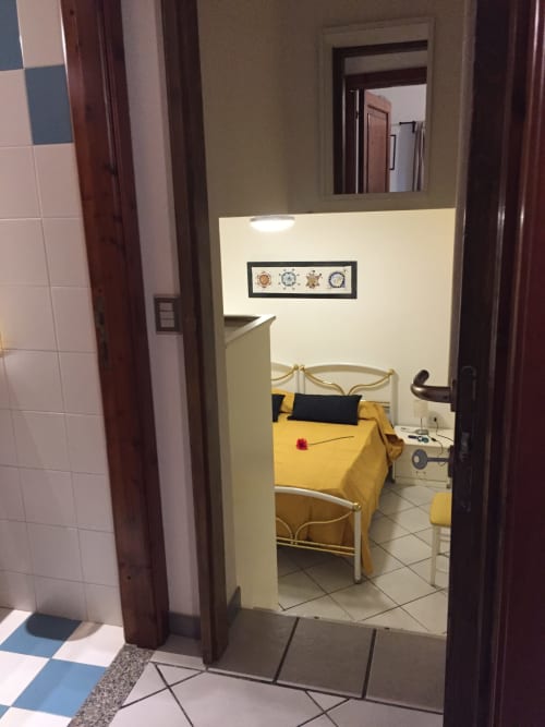 Casa Arborea B bedroom in Orosei with yellow bedding, nautical decor, and open doorway to bathroom area