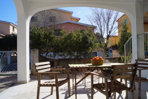 Sunny veranda with wooden furniture and orange fruit basket at Orosei apartment Sa Domo De Mannoi
