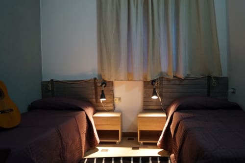 Twin beds with dark linens in Orosei apartment, wooden headboards with hanging lamps and nightstands