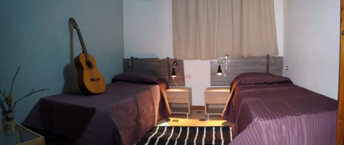 Twin bedroom in Orosei apartment with acoustic guitar, dark bedding, wooden nightstands, and striped rug