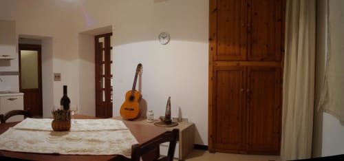 Orosei apartment dining area with acoustic guitar, wooden furniture, and open-plan living space