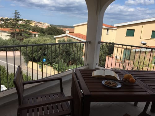 Veranda seating at Domo De Mannoi Alto in Orosei, with armchairs, table, open book, and hillside village views