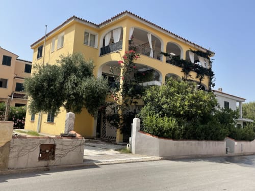 Yellow Mediterranean villa in Orosei with arched windows, terraces, and lush greenery - Sa Domo De Mannoi apartment rental