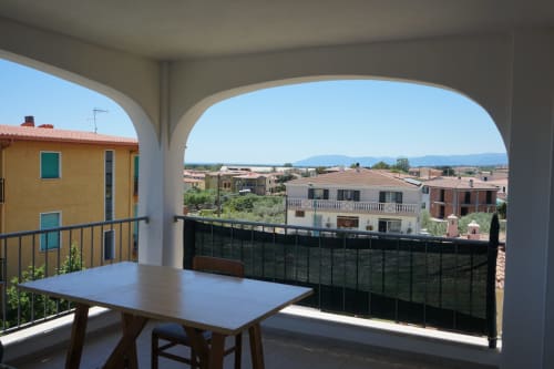 Covered veranda with dining table overlooking Orosei town and Mediterranean landscape, Sa Domo De Mannoi apartment.