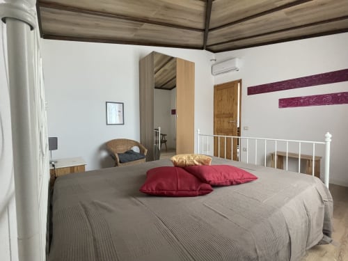 Bedroom at Sa Domo De Mannoi in Orosei with white bed, burgundy pillows, wooden wardrobe, and modern amenities