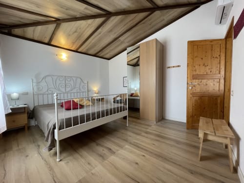 Spacious bedroom at Sa Domo De Mannoi apartment in Orosei with metal bed frame, wooden wardrobe, pine door and herringbone