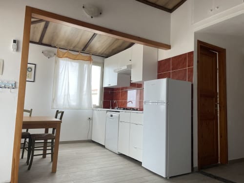 Modern kitchen and dining area in Sa Domo De Mannoi apartment, Orosei with white appliances and red tile backsplash