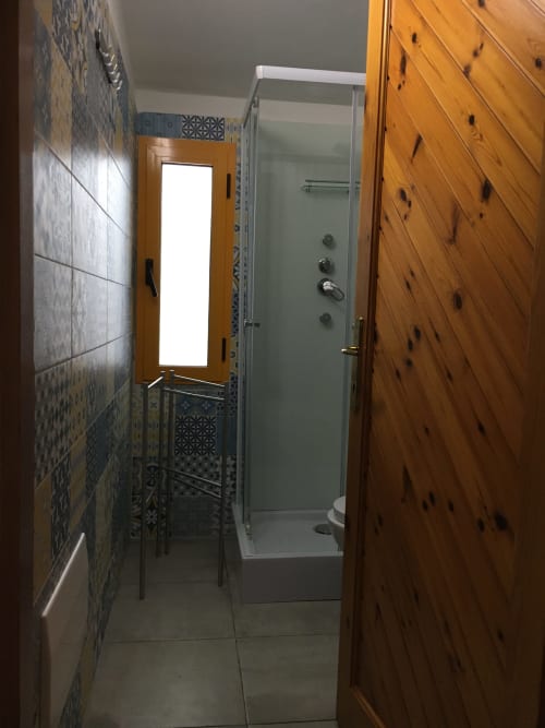 Bagno moderno in Casa Arborea A presso Loddo Paola, Orosei con doccia, porte in legno e piastrelle decorative