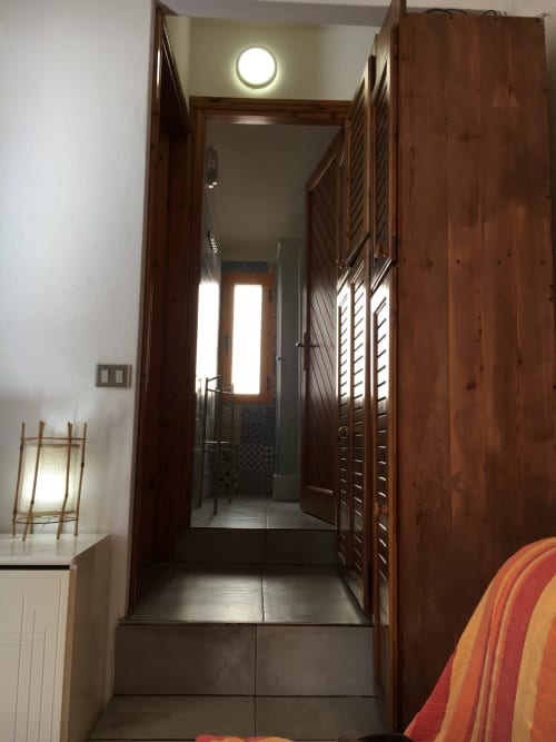 Corridoio con porte in legno e pavimento in piastrelle scure presso Casa Arborea A, alloggio a Orosei