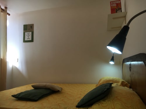 Camera da letto presso Loddo Paola a Orosei con letto, cuscini neri, lampada da scrivania e arte murale