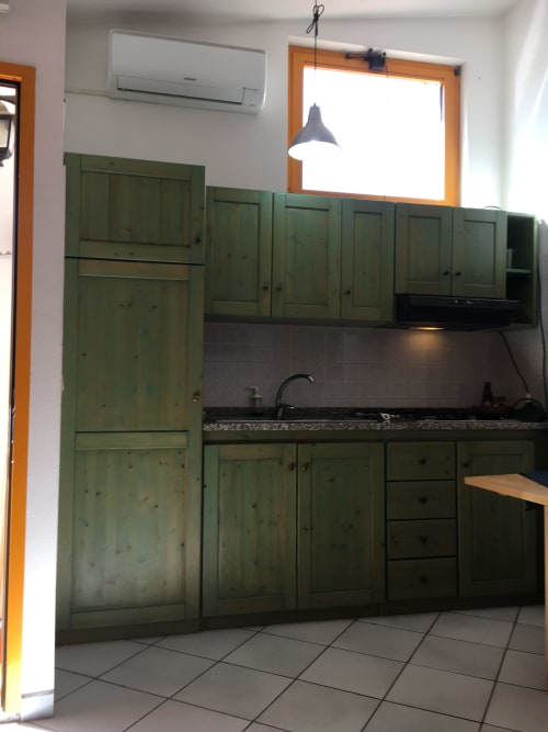 Cucina con mobili verde salvia, piano di lavoro e lavello scuri nella casa vacanze Casa Arborea A di Orosei