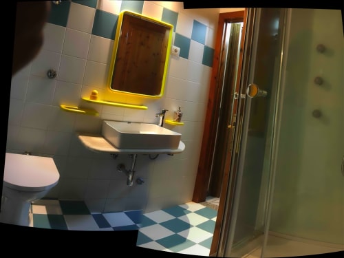 Modern bathroom in Casa Arborea B apartment, Orosei with yellow neon mirror, white vessel sink, and colorful checkered floor