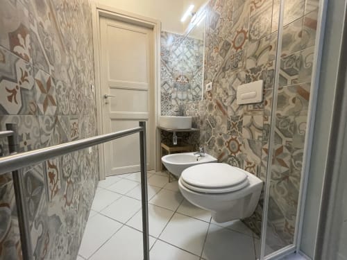 Modern bathroom in Casa Arborea apartment at Loddo Paola, Orosei featuring decorative tiled walls, toilet, bidet, and sink