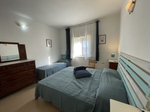 Spacious bedroom at Sa Domo De Mannoi in Orosei with city view, wooden furniture, and modern amenities