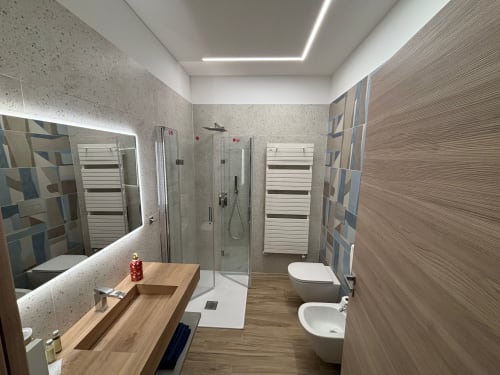 Bagno moderno a La Dimora Di Ipno con vanità in legno, box doccia in vetro, scaldasalviette e pareti rivestite