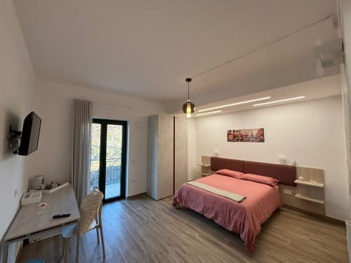Camera moderna a La Dimora Di Ipno a Vallata con biancheria rosa, accesso al balcone, TV e vista montagna