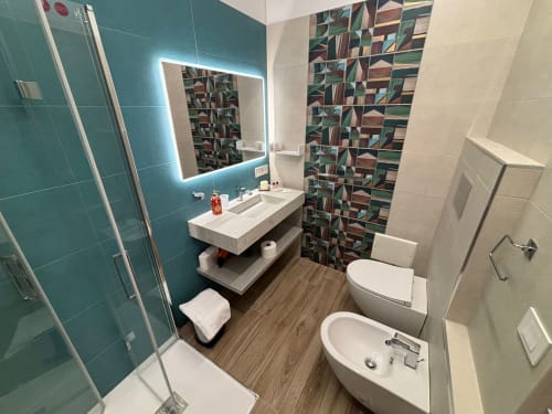 Bagno moderno a La Dimora Di Ipno a Vallata con piastrelle turchesi, specchio illuminato, tenda doccia geometrica e effetto legno
