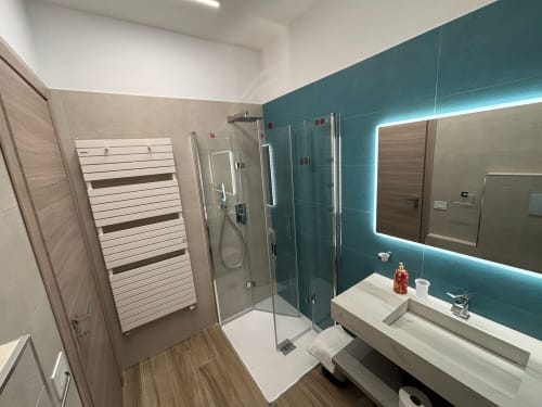 Bagno moderno a La Dimora Di Ipno con parete azzurra, doccia walk-in, scaldasalviette e specchio illuminato