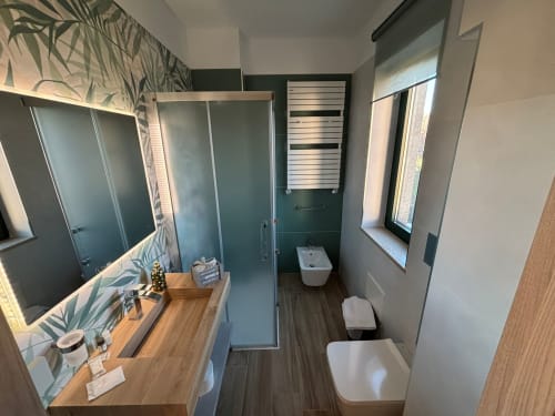 Bagno moderno a La Dimora Di Ipno a Vallata con mobile lavabo in legno, doccia a fondo aperto, toilette, scaldasalviette e luce naturale