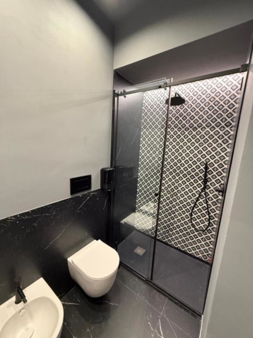 Bagno moderno a Volta 70 Napoli con pavimenti in marmo nero, water bianco e box doccia con motivi geometrici