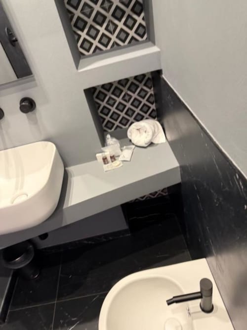 Bagno moderno presso Volta 70 Napoli con lavabo bianco, bidet, wc e piastrelle di marmo nero con griglie di ventilazione