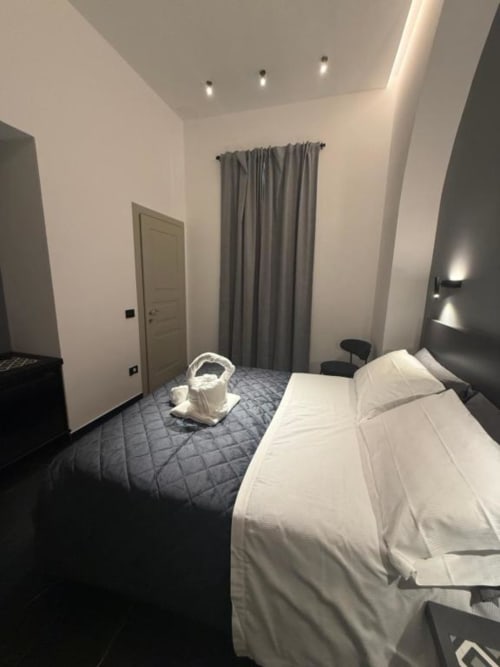 Camera Deluxe moderna a Volta 70 bed and breakfast a Napoli con muri bianchi, tende grigie e illuminazione contemporanea