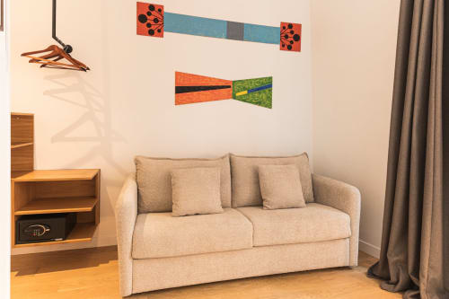 Canapé beige dans une suite d'hôtel parisien avec œuvres d'art colorées et mobilier en bois à l'Hôtel Louvre Richelieu