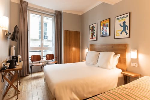 Chambre Triple Comfort à l'Hôtel Louvre Richelieu à Paris avec lits jumeaux, tête de lit en bois et vue sur la ville