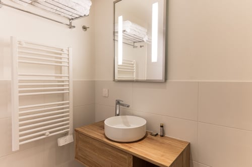 Salle de bain moderne à l'Hôtel Louvre Richelieu Paris avec vasque blanche, sèche-serviettes chauffant et miroir rétroéclairé
