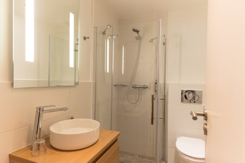 Salle de bains moderne de l'Hôtel Louvre Richelieu Paris avec lavabo rond, douche et sèche-serviettes électrique