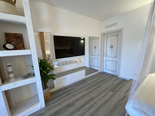 Soggiorno moderno a Villa Carrie Porto Pozzo con TV a parete, librerie bianche e pavimento in legno