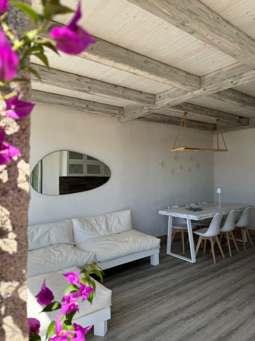 Interno moderno di appartamento a Villa Carrie Porto Pozzo con divano bianco, travi in legno, zona pranzo e fiori fucsia