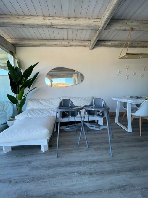 Interno moderno dell'appartamento a Villa Carrie Porto Pozzo con letto, sedie da pranzo, pianta in vaso e travi in legno