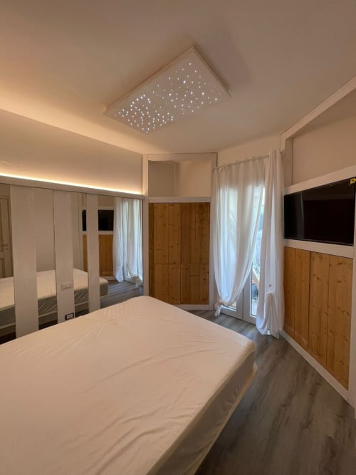 Camera da letto moderna a Villa Carrie Porto Pozzo con soffitto stellato, armadio in legno e TV schermo piatto