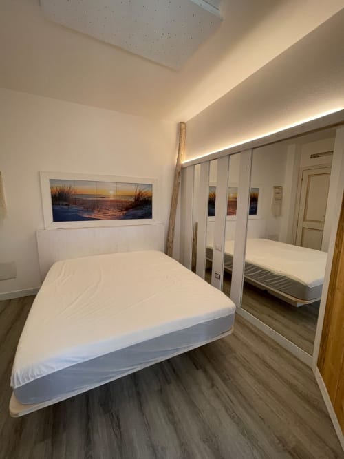 Camera moderna di Villa Carrie Porto Pozzo con letto bianco, armadio con specchio e quadro tramonto marino a Santa Teresa