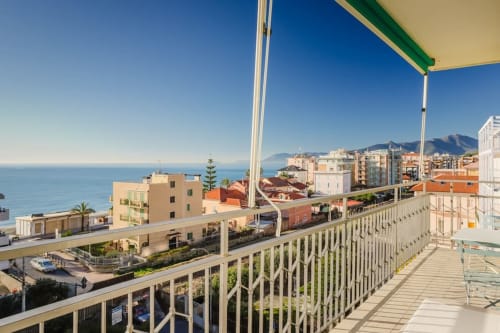 Residenza la Pietra balcony overlooking Pietra Ligure's Ligurian coast, mountains, and colorful buildings