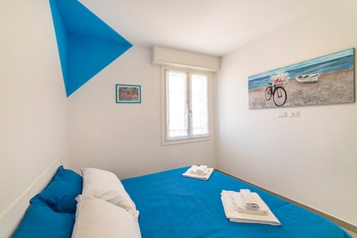 Bright bedroom at Residenza la Pietra with blue bedding, coastal decor, and geometric blue wall art in Pietra Ligure