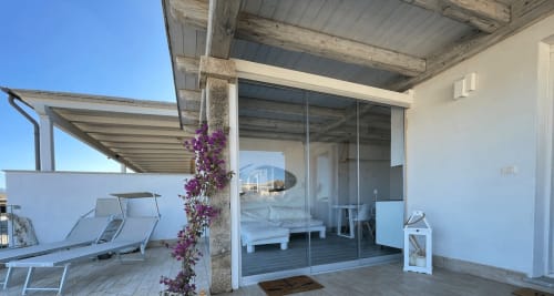 Terrazza fronte mare moderna di Villa Carrie Porto Pozzo con lettini, fiori viola e vista sul mare