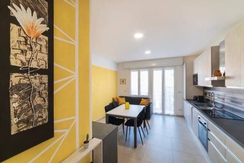 Modern kitchen and dining area at Residenza la Pietra with yellow accents, white table, and sliding doors in Pietra Ligure