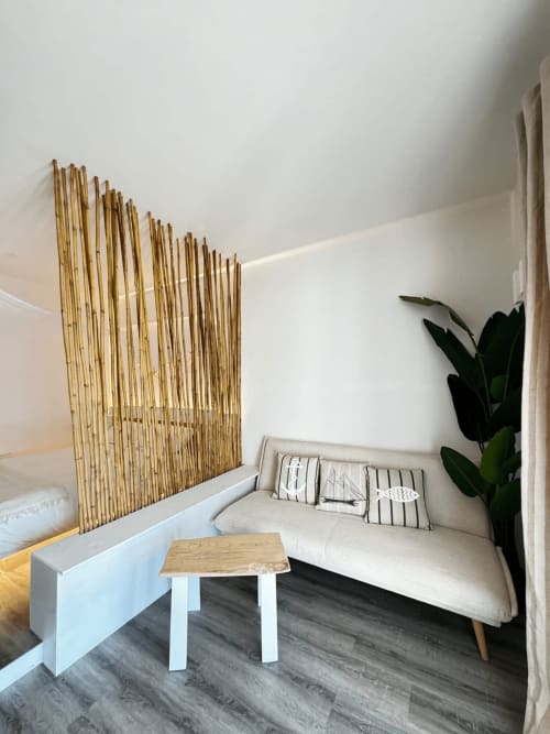 Camera moderna a Villa Carrie Porto Pozzo con divano beige, paravento in bambù, tavolino in legno e pianta in vaso