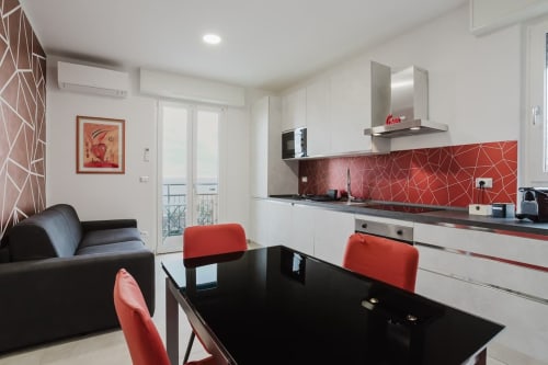 Modern studio at Residenza la Pietra in Pietra Ligure featuring red geometric backsplash, black dining table, and