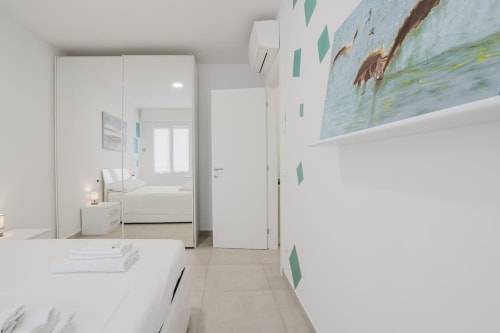 Modern bathroom at Residenza la Pietra hotel in Pietra Ligure with white vanity, mirror, and nature artwork