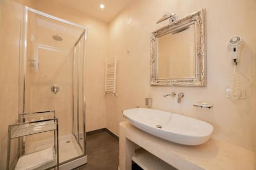 Modern bathroom in Deluxe Sea View Room at Al Mirador Resort, Fasano, with oval sink, framed mirror, and glass shower