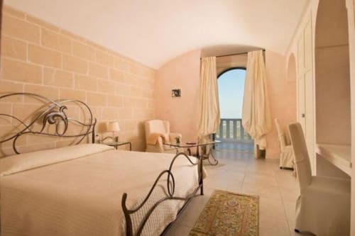 Luxuszimmer mit Meerblick im Al Mirador Resort in Fasano mit schmiedeeisernem Bett, Gewölbedecke und Balkon mit Meerblick