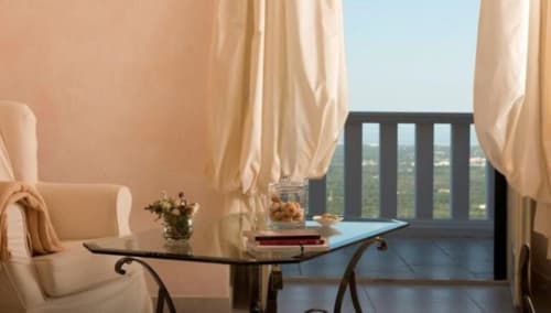 Deluxe Sea View Room at Al Mirador Resort in Fasano with cream drapes, armchair, desk, and balcony overlooking Italian
