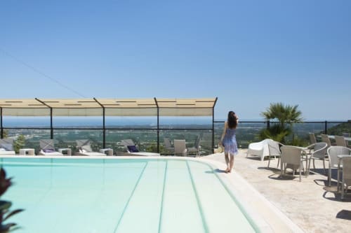 Frau am Infinity Pool mit Blick auf die Landschaft von Fasano im Al Mirador Resort mit Liegestühlen und Palme
