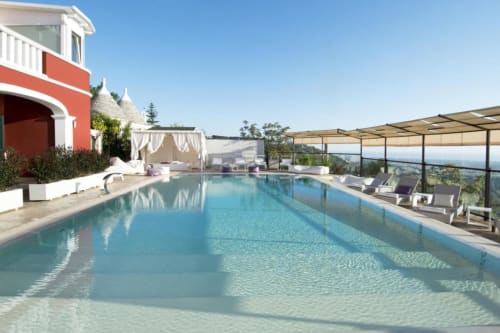Luxus-Infinity-Pool des Al Mirador Resort mit Sonnenliegen, Pergola und Panoramablick auf die Fasano-Landschaft unter klarem Himmel