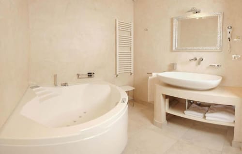 Luxurious bathroom in Suite Mirador at Al Mirador Resort, Fasano, featuring corner spa tub, vessel sink, heated towel rack,