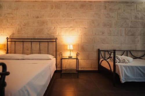 Al Mirador Resort junior suite in Fasano with two metal frame beds, terracotta walls, warm lighting, and dark tile flooring
