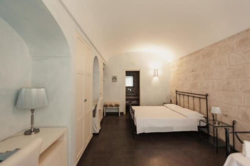 Spacious Junior Suite at Al Mirador Resort in Fasano with iron bed frame, desk lamp, and pool view access